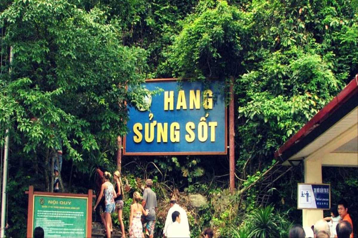 Visitor walking along a stone path inside Sung Sot Cave Halong Bay with natural light filtering through openings