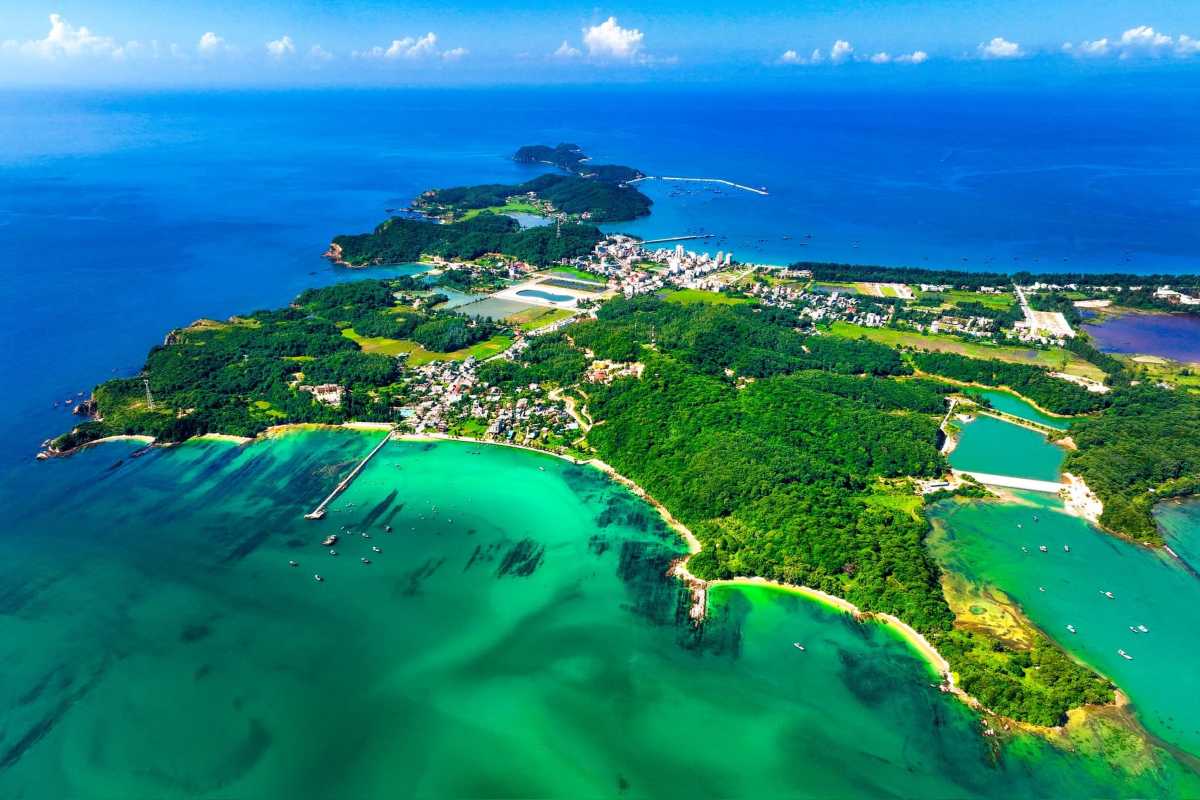 Traditional fishing boats anchored near rocky shores surrounded by green forests on Quan Lan Island