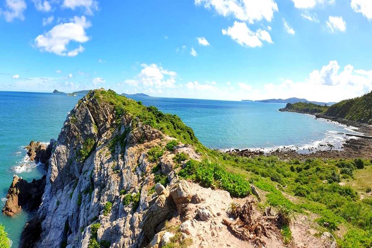 Wide panoramic view of lush greenery and rocky coastline on Quan Lan Island