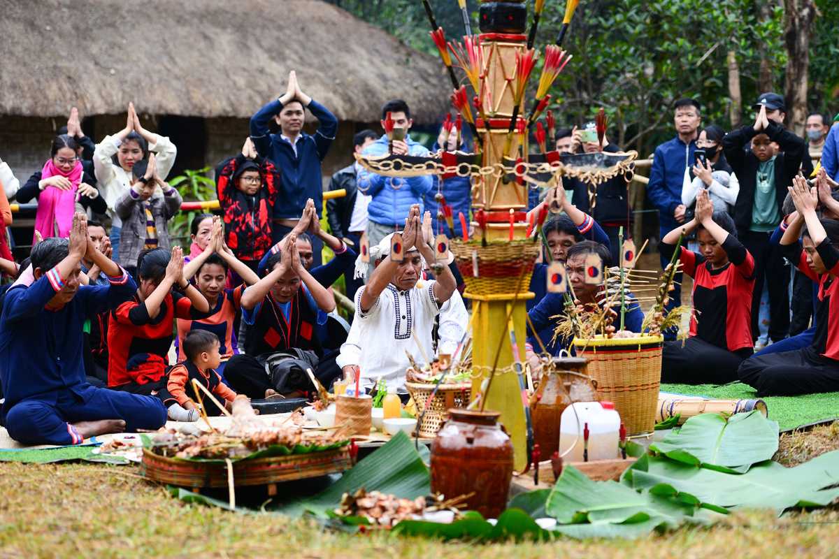 Raglai Prayer Ceremony for Ancestors Raglai villagers raise hands in prayer around an altar with food, rice, and symbolic totems during a spiritual community festival.