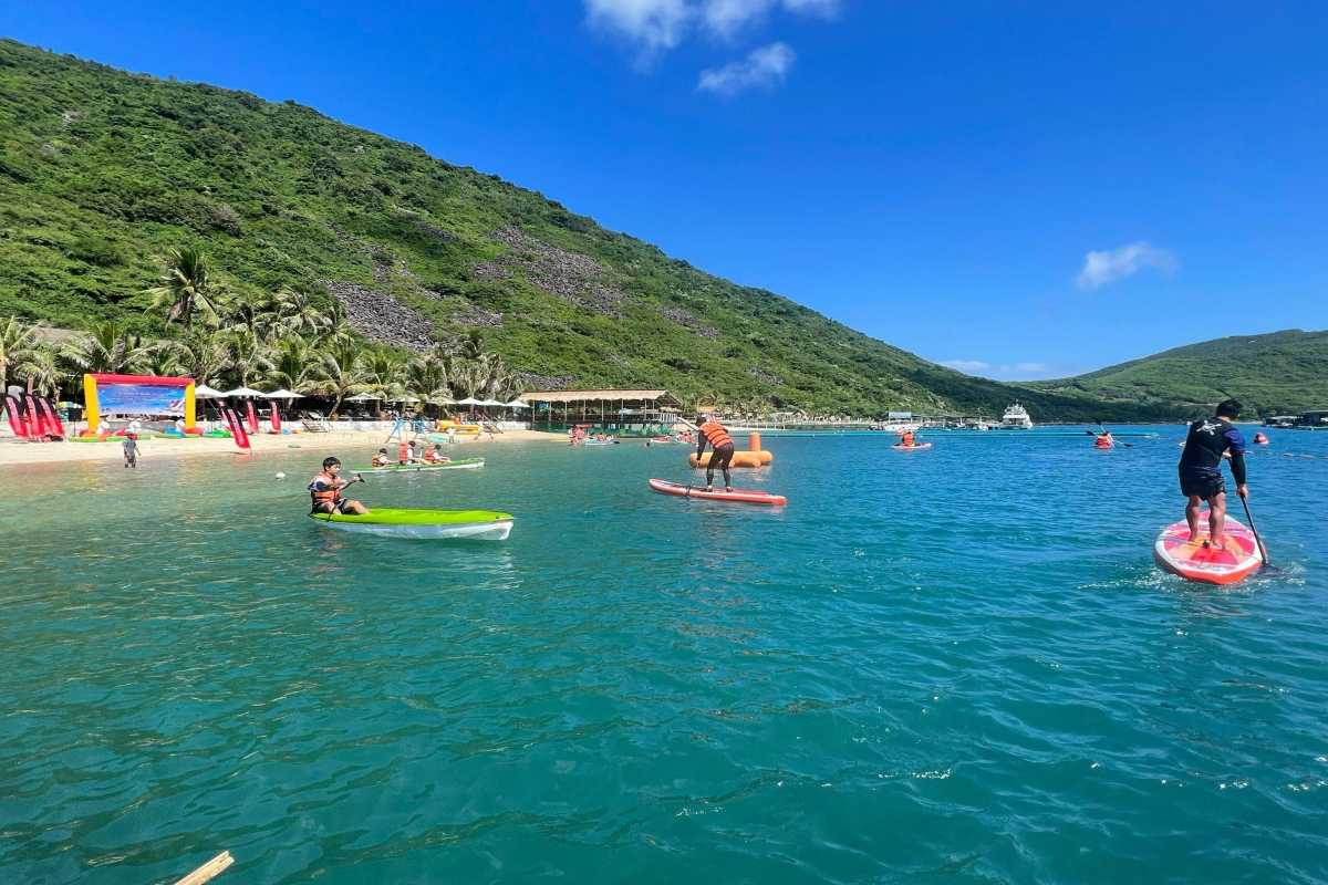 Kayakers enjoying clear blue waters at Robinson Beach Nha Trang with lush green hills in the background