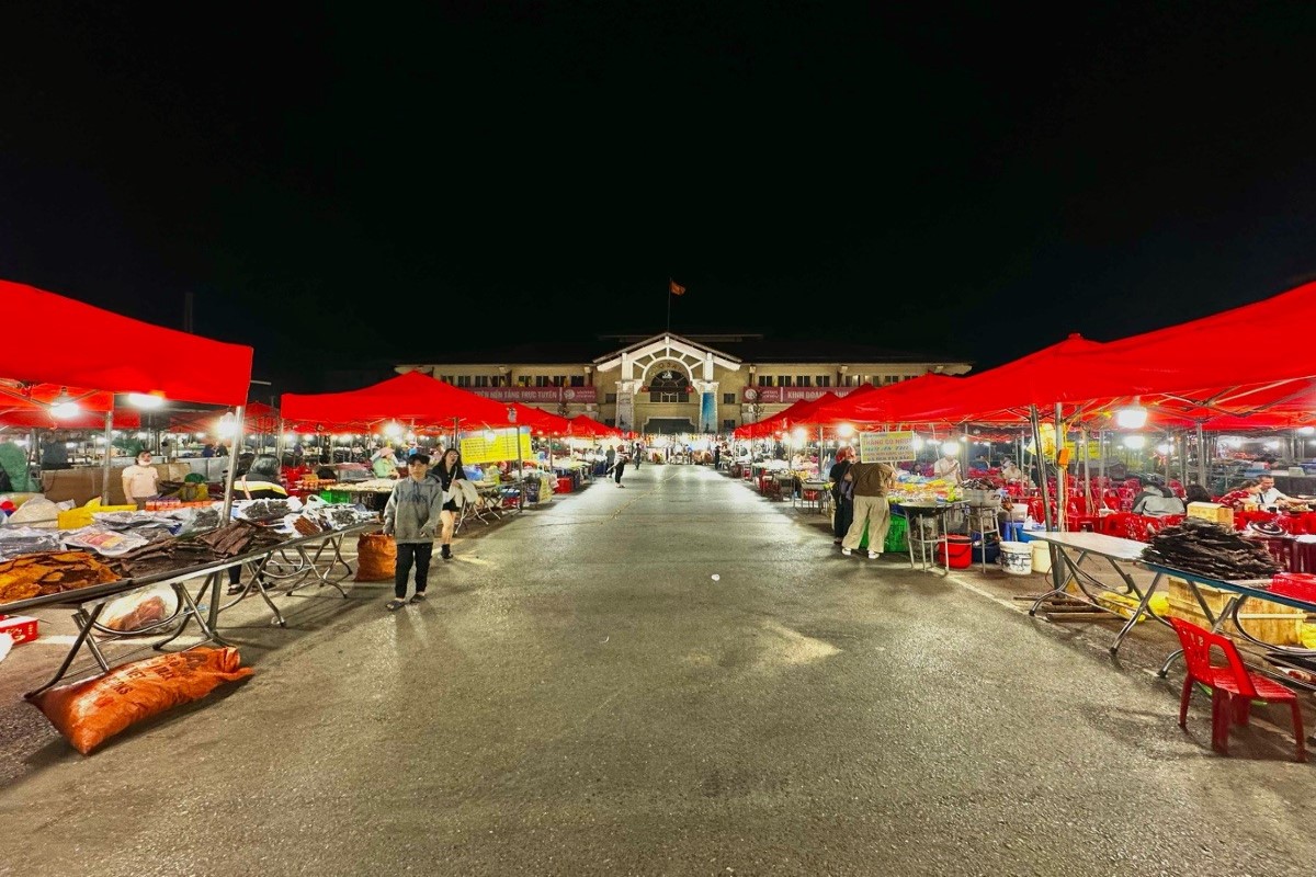 A scenic view of Sapa Night Market with red tents and people exploring the stalls, showcasing the lively nighttime atmosphere.