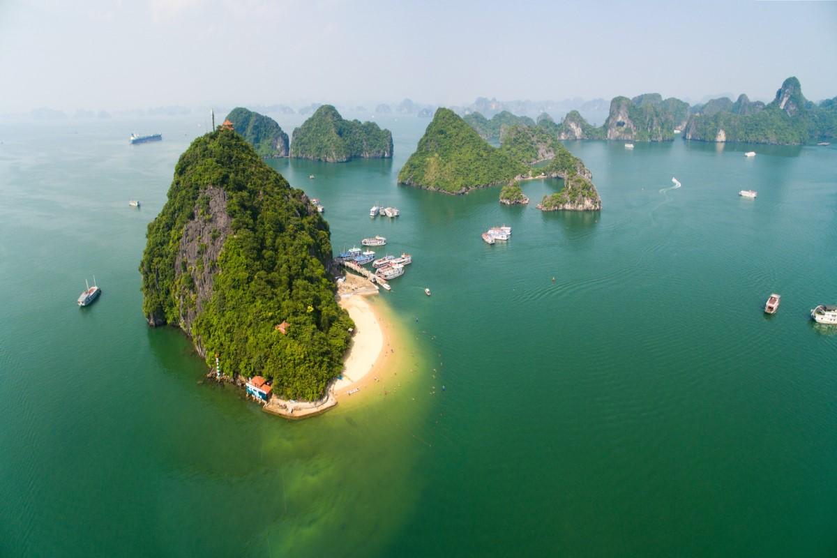 Aerial view of Titov Island with lush greenery and a sandy beach.