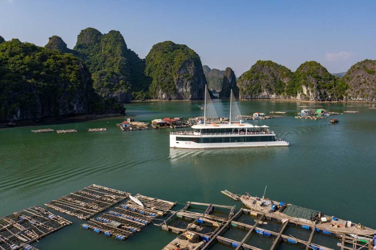 Scenic landscape showing floating village and limestone cliffs at Tung Sau Pearl Farm Halong Bay, with calm green waters