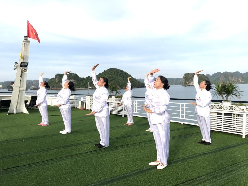 Senior Group Tai Chi on Halong Bay Deck A senior group performing Tai Chi on a Halong Bay cruise deck under peaceful skies.