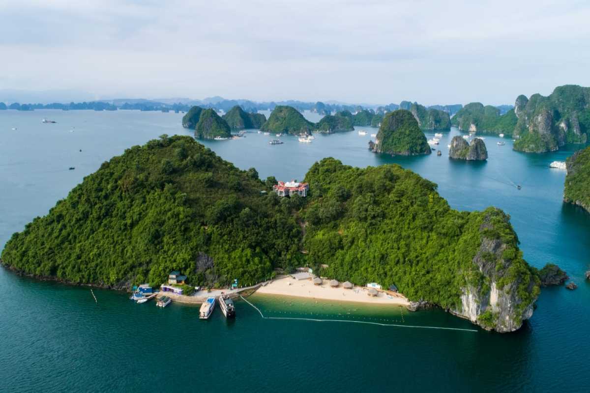 Soi Sim Island Halong Bay sandy beach featuring loungers and thatched huts under the shade
