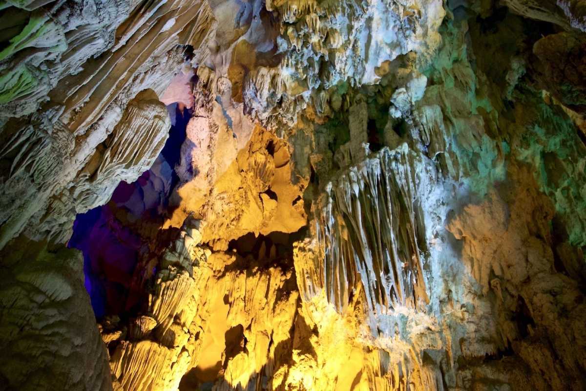 Colorful lights illuminate the unique rock formations inside Sung Sot Cave Halong Bay, enhancing the cave’s beauty.