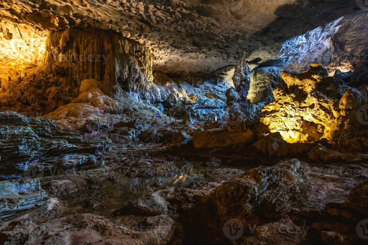 Illuminated stalactites and stalagmites in Sung Sot Cave Halong Bay, showing intricate geological details.