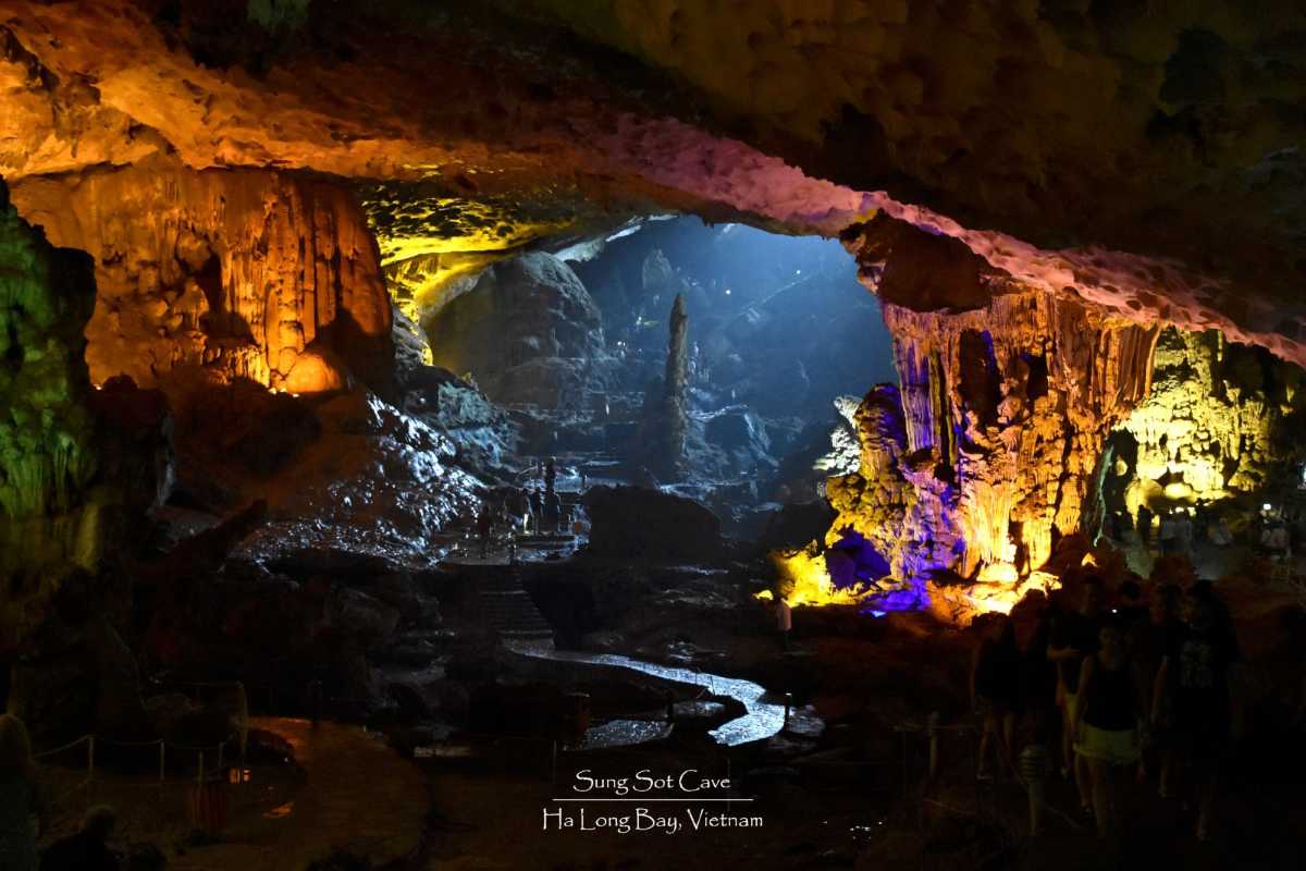 Tourists exploring the illuminated interior of Sung Sot Cave Halong Bay, walking along safe pathways.