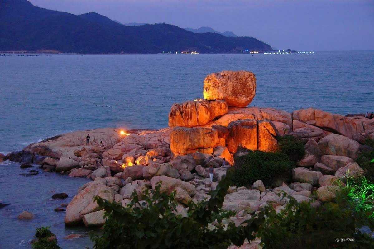Hon Chong Promontory rocks illuminated at dusk with ocean waves nearby