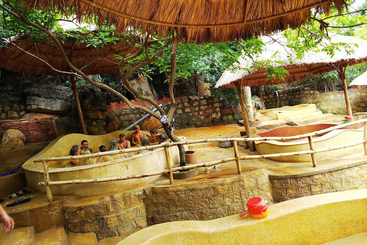 Couples enjoying Thap Ba mud bath Two guests relax in a mineral mud bath at Thap Ba, covered head to toe in therapeutic spa mud