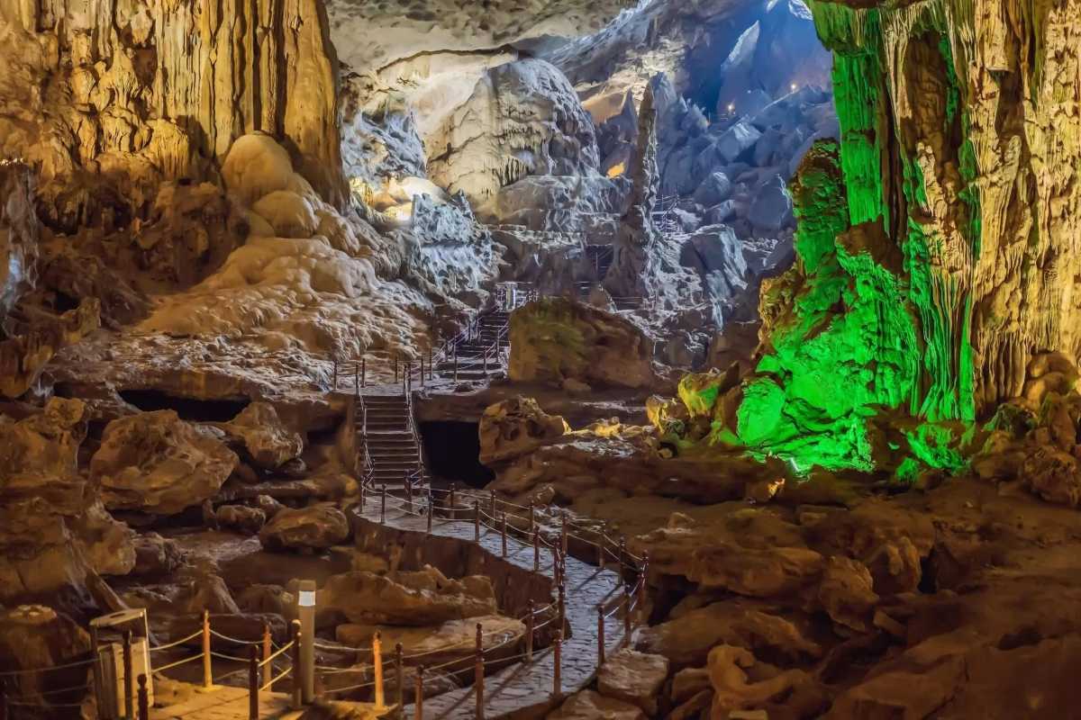 Green and blue lighting effects illuminating rock formations inside Thien Canh Son Cave