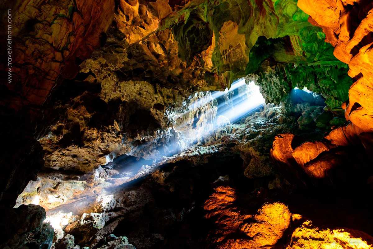 Sunlight beams streaming through an opening in Thien Cung Cave Halong Bay, highlighting cave textures