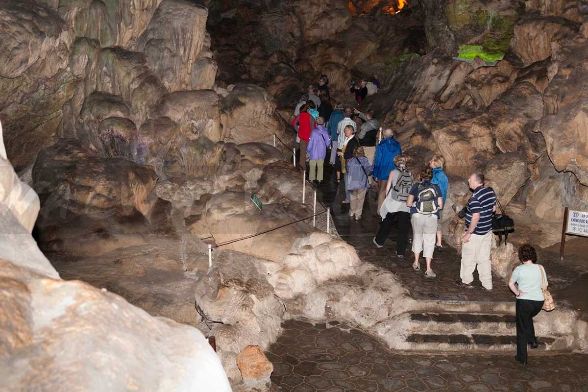 Visitors exploring Thien Cung Cave Halong Bay along a paved pathway highlighting geological features