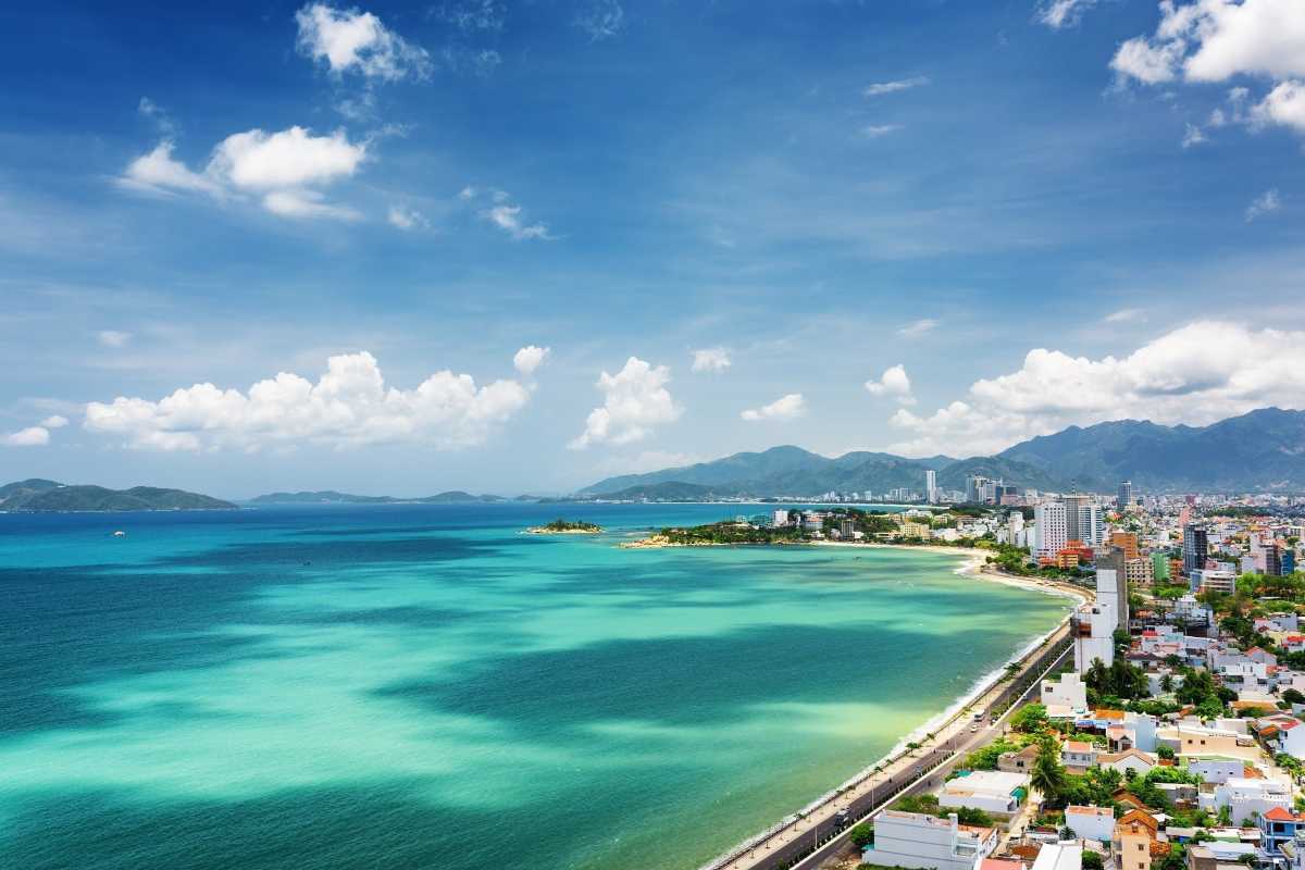 Panoramic coastal view of Tien Beach in Nha Trang with turquoise water and distant mountains.