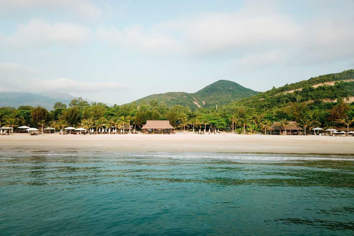 White sandy beach and blue sea at Tien Beach Nha Trang with beach umbrellas and shaded areas.