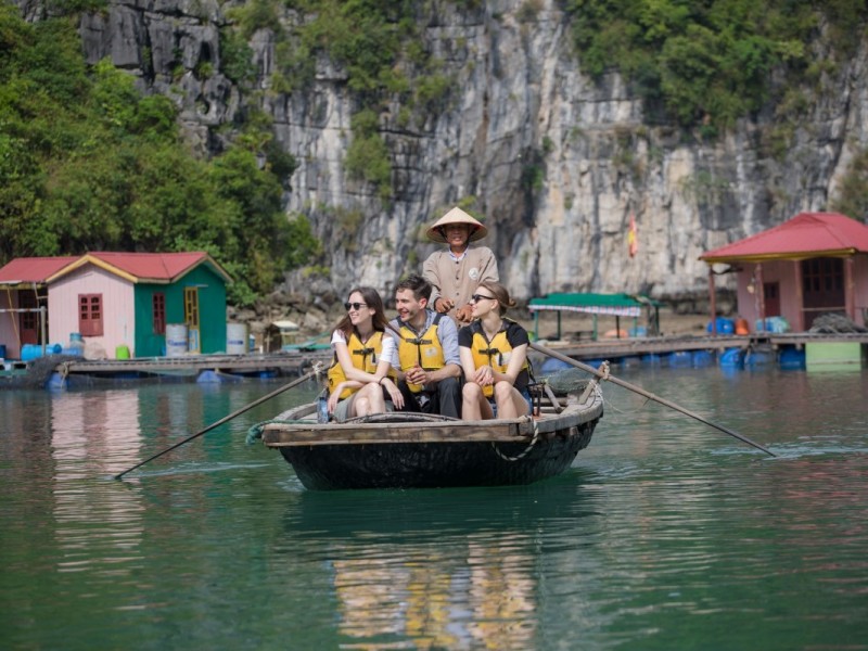 Tourists Enjoying a Bamboo Boat Ride in Cua Van Tourists enjoy a bamboo boat ride in Cua Van Floating Village, surrounded by limestone cliffs and greenery.