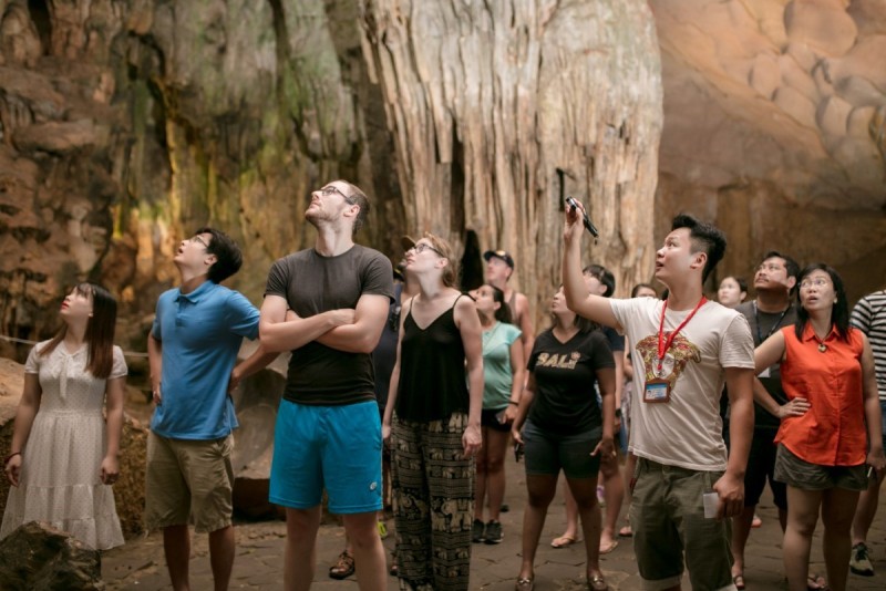 Tourists Exploring Sung Sot Cave in Halong Bay Group of tourists looking up at the limestone formations inside Sung Sot Cave, Halong Bay.