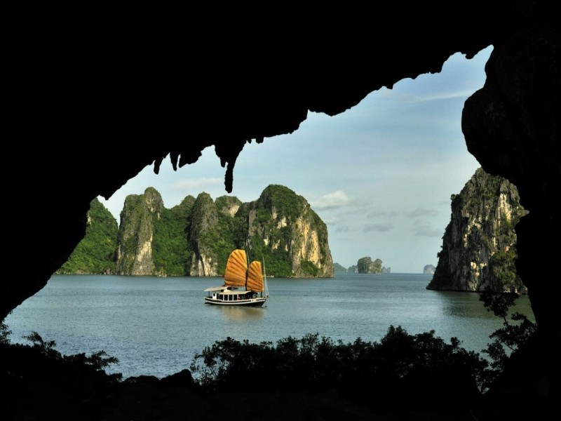 Tourists Exploring the View from Drum Cave in Halong Bay Tourists standing inside Drum Cave enjoying the panoramic view of Halong Bay's limestone formations.
