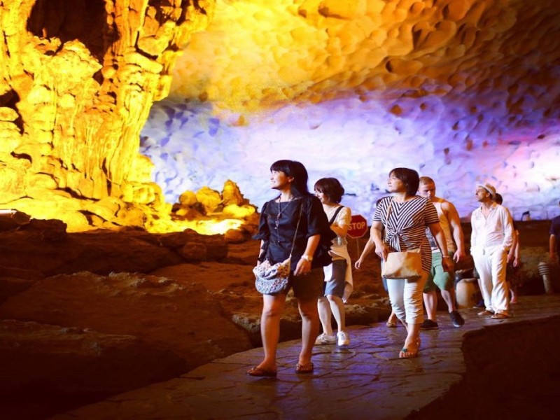 Tourists Exploring Trinh Nu Cave A group of tourists exploring the beautifully lit interior of Trinh Nu Cave in Halong Bay.