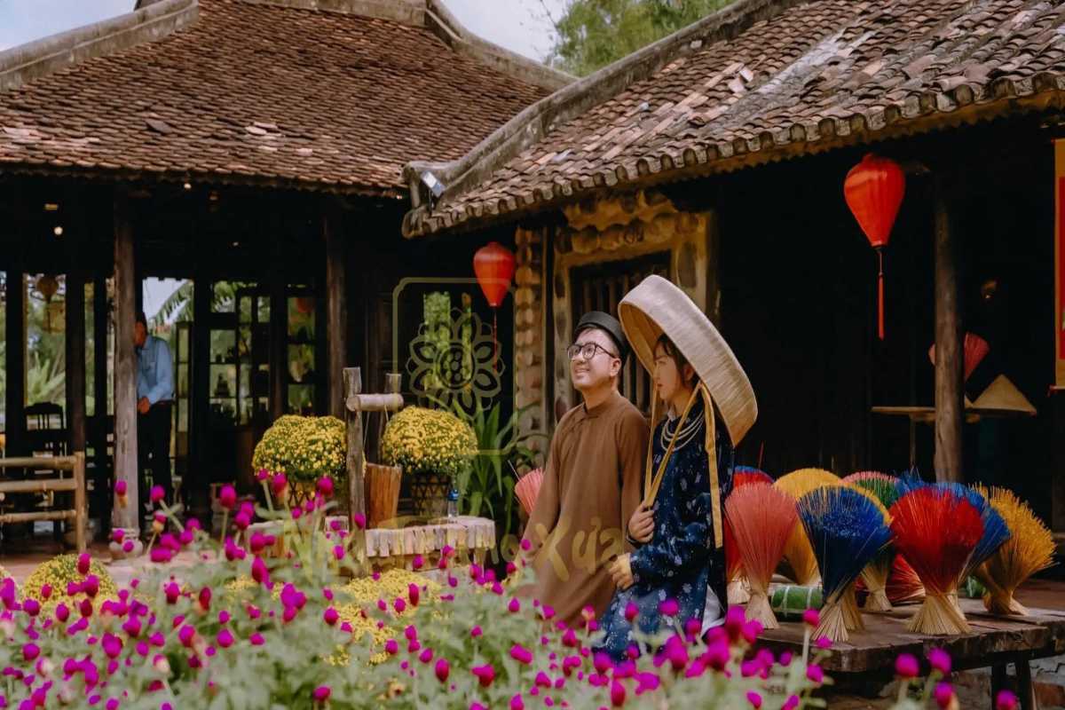 Couple in traditional dress at Phu Vinh Visitors in traditional attire pose near incense bundles and flowers at Phu Vinh Ancient Village