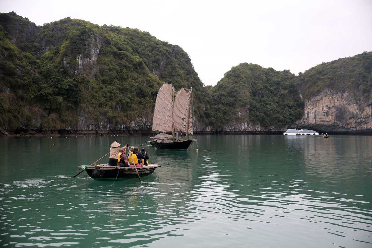 Traditional wooden junk boat sailing near limestone karsts in Bai Tu Long Bay