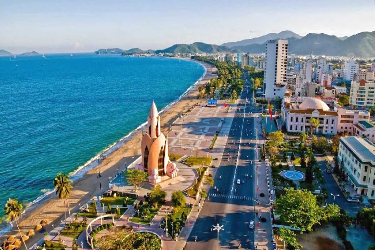Tram Huong Tower aerial wide view High-angle image showing Tram Huong Tower, the full beach curve, and mountain horizon in one wide shot