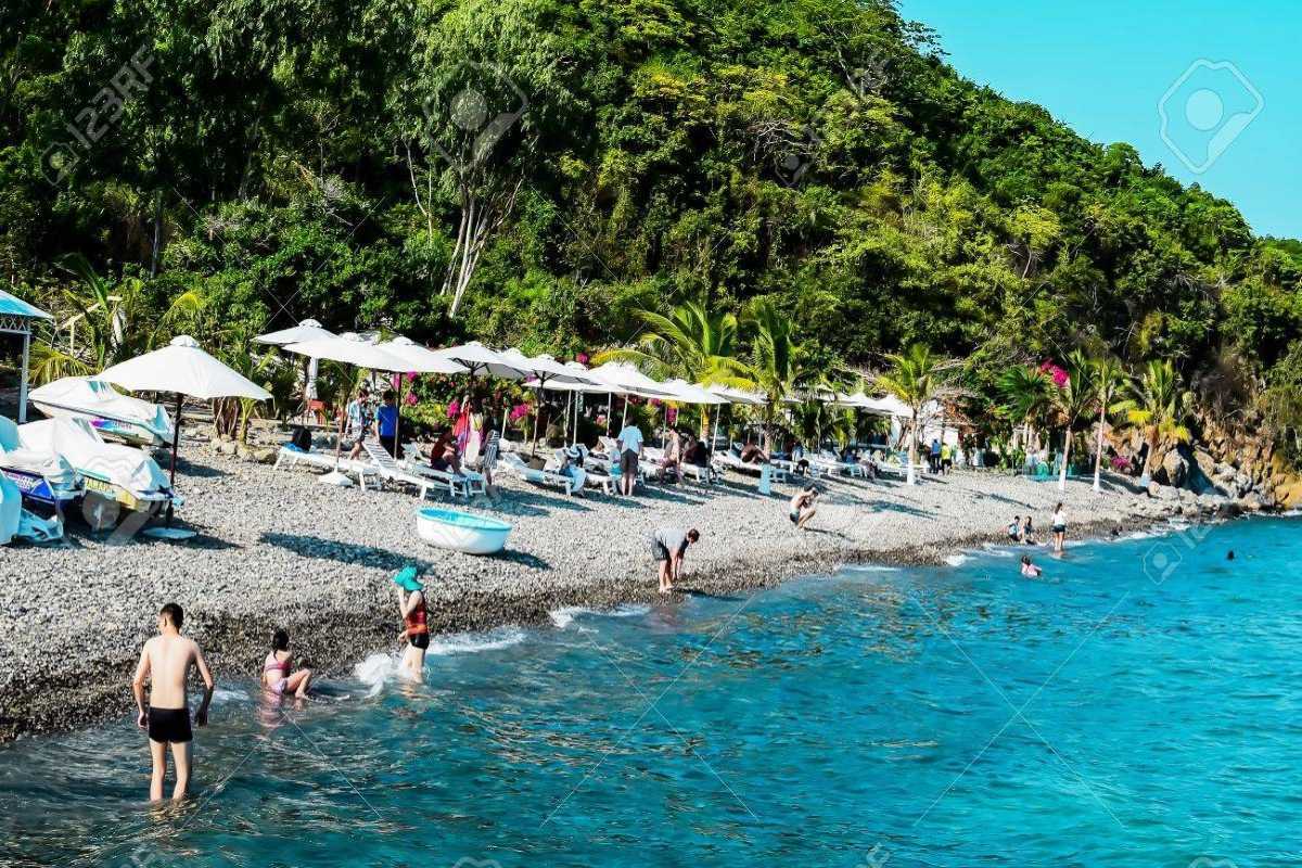 Tranh Beach Nha Trang Pebble Shoreline Visitors enjoying the pebble beach and sun umbrellas at Tranh Beach Nha Trang under clear blue skies