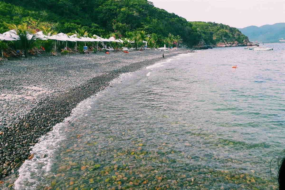 Tranh Beach Nha Trang Rocky Beach View Pebble-covered beach with calm waves and green hills surrounding Tranh Beach Nha Trang