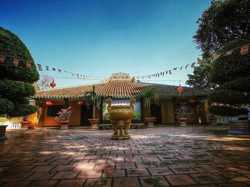 Tranquil Courtyard of Giac Lam Pagoda Courtyard view of Giac Lam Pagoda with plants, lanterns, and flags