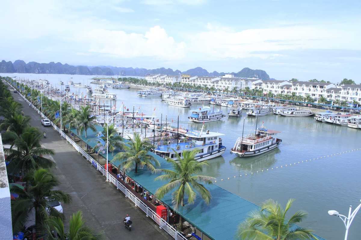 Waterfront walkway at Tuan Chau Harbor Ha Long Bay lined with palm trees and tourist facilities