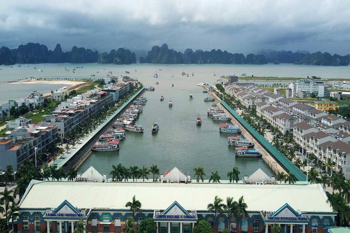 Marina at Tuan Chau Harbor Halong filled with boats and yachts docked alongside the waterfront residential area.