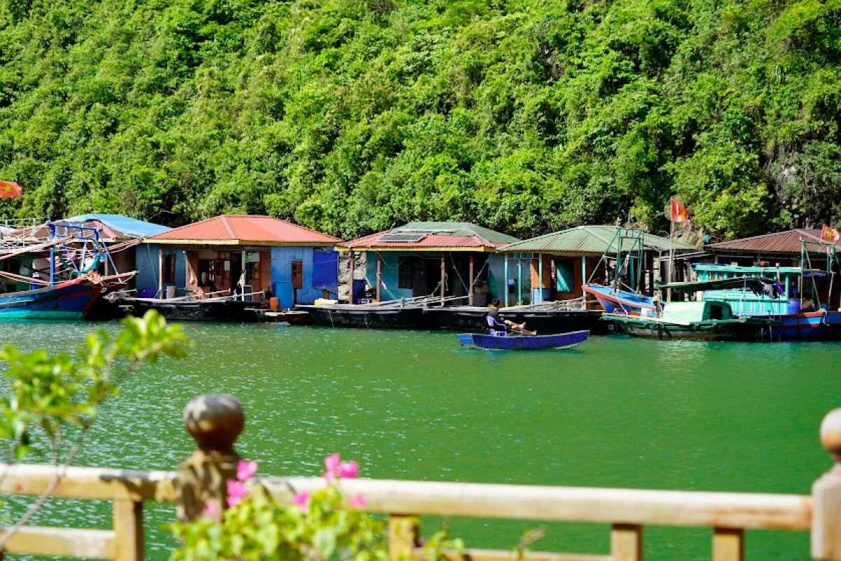 Colorful floating houses at Tung Sau Pearl Farm Halong Bay with lush green karsts in the background