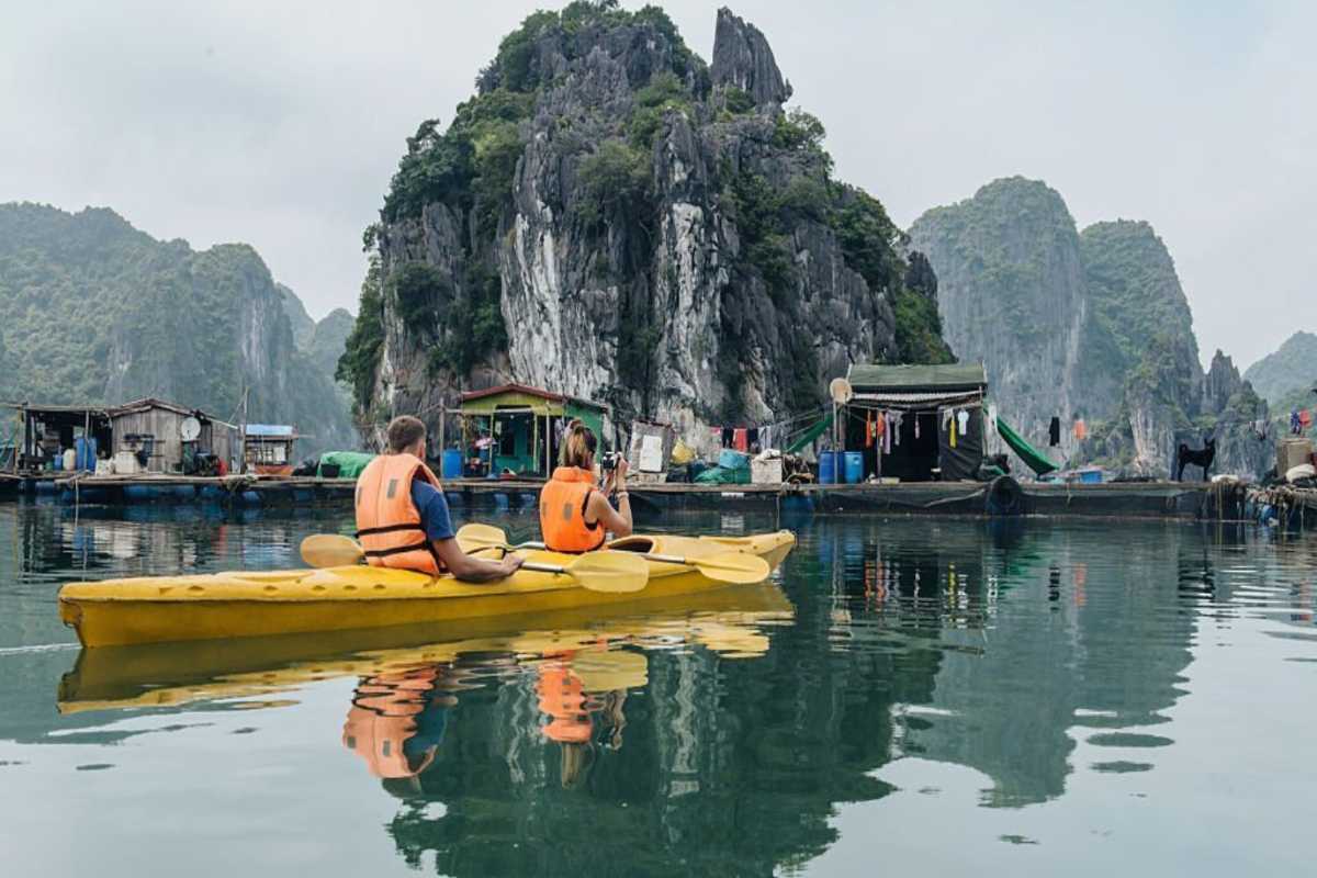 Rows of buoys and pearl farming equipment floating on calm waters at Tung Sau Pearl Farm Halong Bay, backed by green cliffs