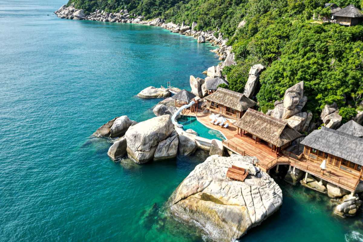 Aerial view of a luxury cliffside resort overlooking clear turquoise water in Van Phong Bay