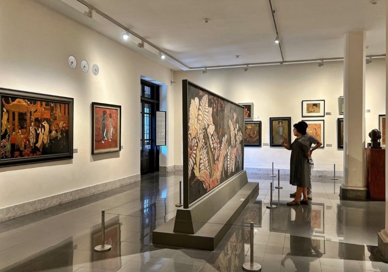 Vietnam National Fine Arts Museum Painting Exhibit Bright exhibit room in Vietnam National Fine Arts Museum featuring traditional Vietnamese paintings with visitors admiring the art.