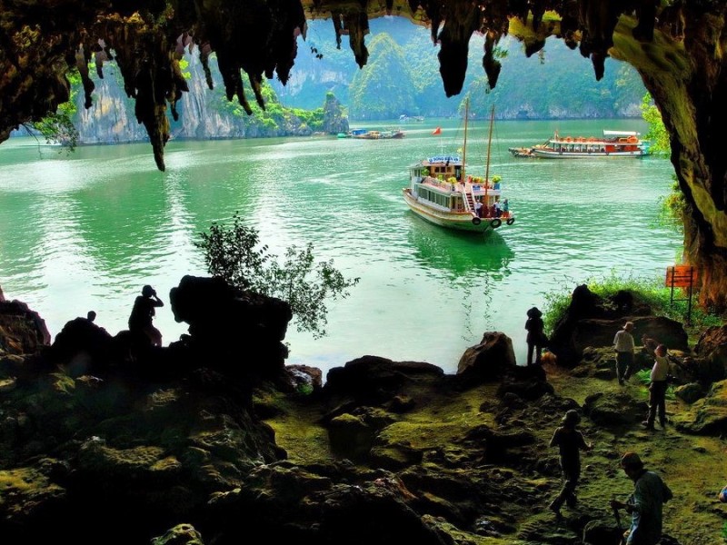 View from inside Bo Nau Cave to Halong Bay waters The view from inside Bo Nau Cave looking out to the emerald waters of Halong Bay with boats and limestone cliffs in the distance.