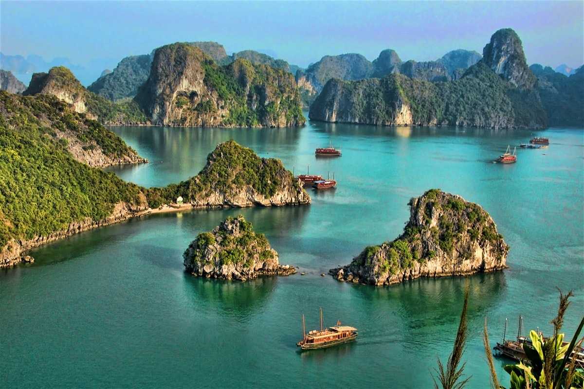 Entrance to Virgin Cave Halong Bay with boats anchored nearby and clear blue waters