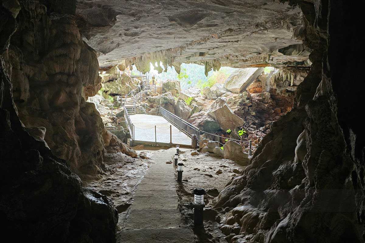 Walkway path inside Virgin Cave Halong Bay surrounded by natural rock formations and cave roof stalactites