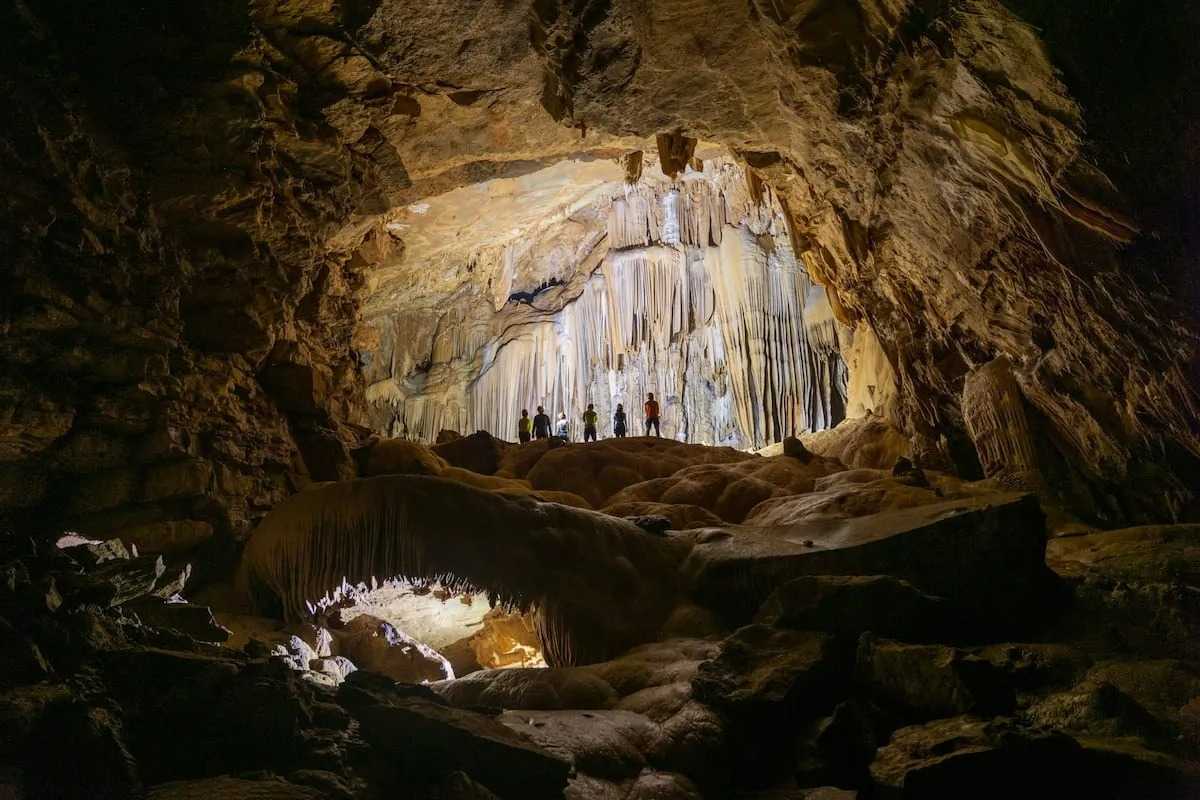Interior of Virgin Cave Halong Bay with illuminated stalactites and visitors admiring natural formations inside the cave