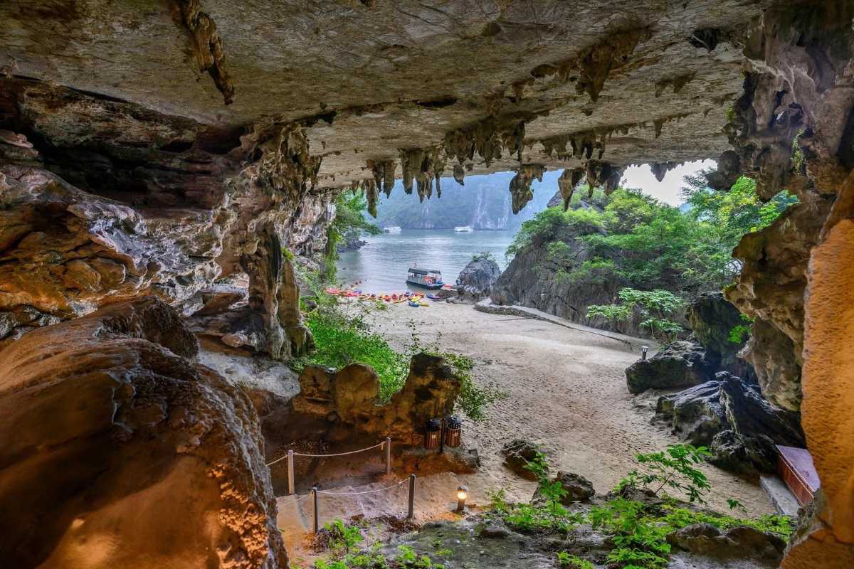 Entrance to Virgin Cave Halong Bay surrounded by rocky cliffs and green vegetation
