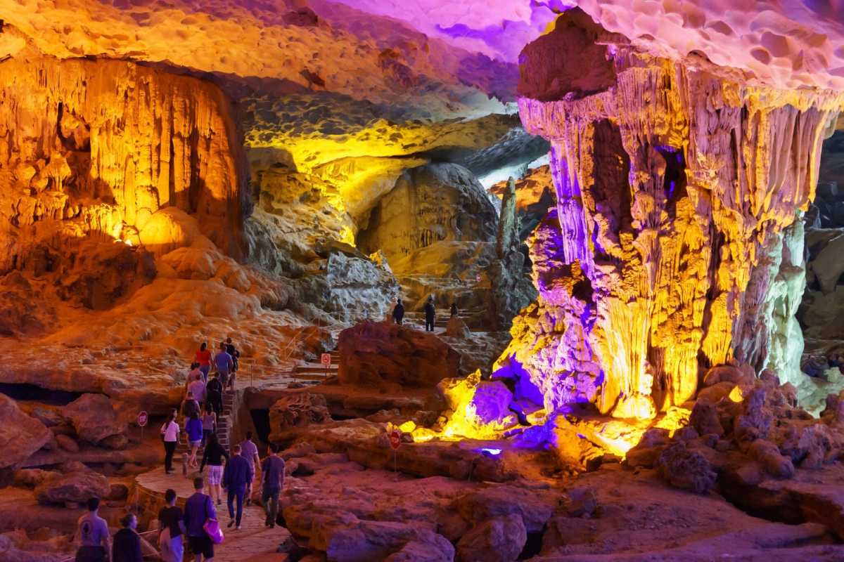 Tourists explore vibrant, colorful cave interiors at Sung Sot Cave Halong Bay on paved walking paths