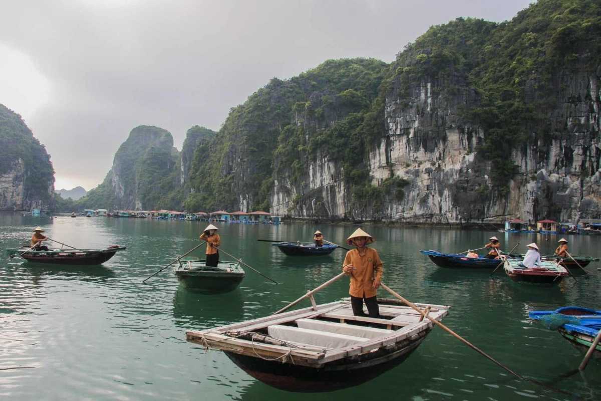 Boat carrying visitors arriving at Vung Vieng Fishing Village on Halong Bay surrounded by limestone karsts
