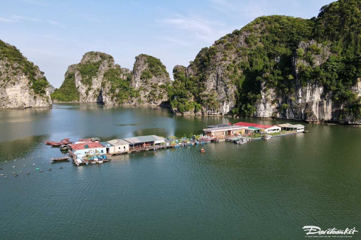 Visitors on a small rowboat touring Vung Vieng Fishing Village with limestone cliffs in the background
