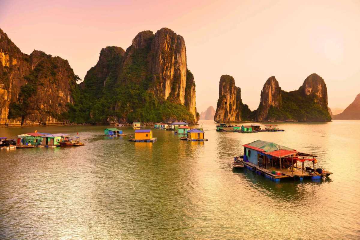 Colorful floating houses at Vung Vieng Fishing Village on Halong Bay with towering limestone islands in background