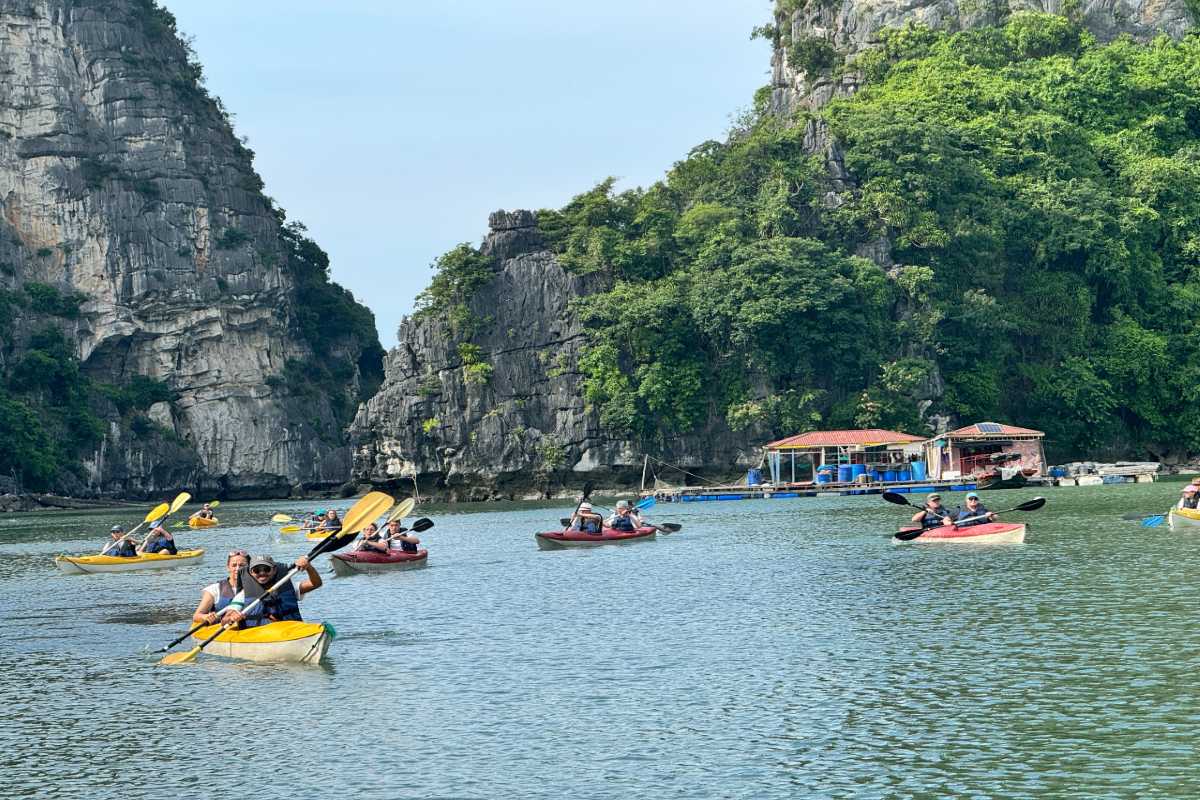 Tourists kayaking through Vung Vieng Fishing Village on Halong Bay surrounded by limestone islands