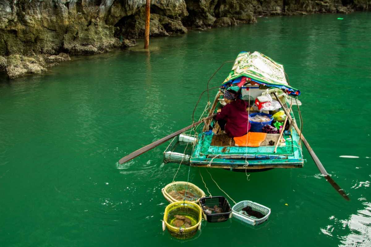 Local boat at Vung Vieng Fishing Village on Halong Bay with vibrant fishing gear and limestone cliffs in background