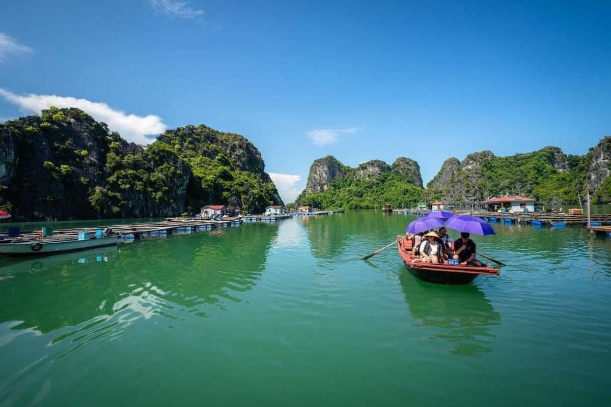 Visitors in rowboats touring Vung Vieng Fishing Village surrounded by limestone cliffs on Halong Bay