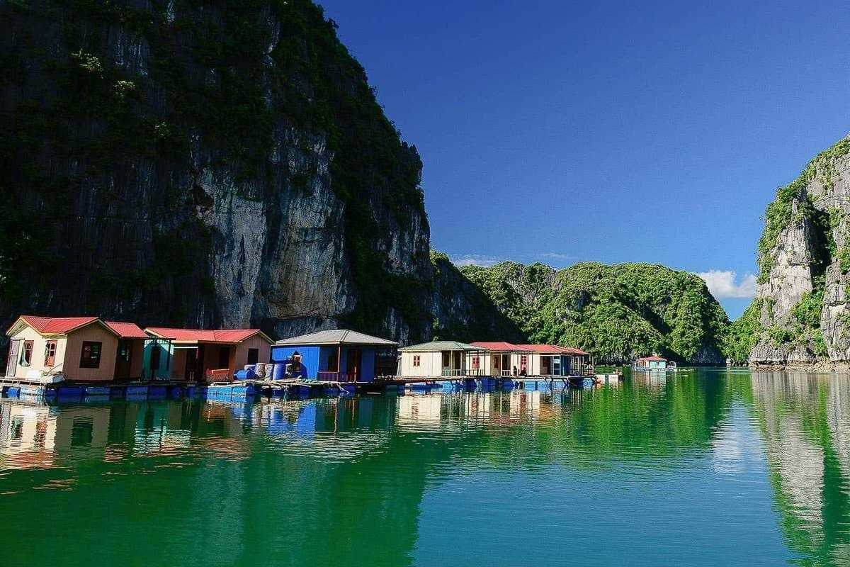 Floating homes of Vung Vieng Fishing Village on Halong Bay surrounded by limestone cliffs and calm emerald water