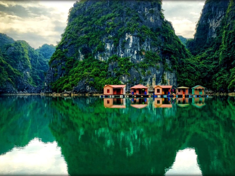 Vung Vieng Fishing Village: Peaceful Floating Homes A peaceful view of floating homes in Vung Vieng Fishing Village, set against dramatic limestone islands in Bai Tu Long Bay.
